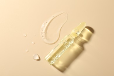 Photo of Glass ampoule with cosmetic product and sample on beige background, top view. Space for text