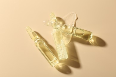 Photo of Glass ampoules with cosmetic product on beige background, flat lay