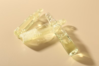Photo of Glass ampoules with cosmetic product on beige background, closeup