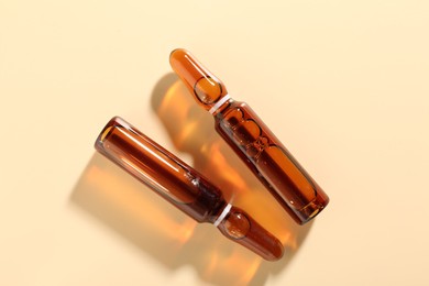 Photo of Glass ampoules with cosmetic product on beige background, flat lay