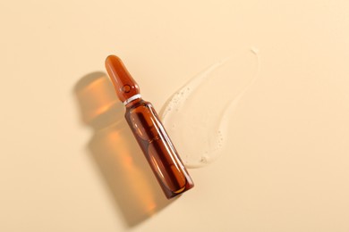 Photo of Glass ampoule with cosmetic product on beige background, top view. Space for text