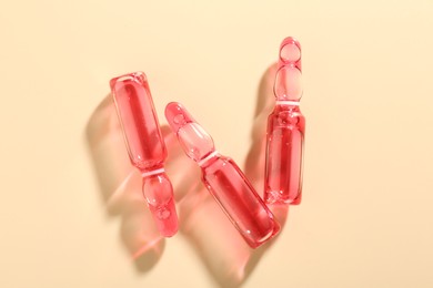 Photo of Glass ampoules with cosmetic product on beige background, flat lay