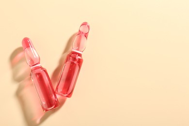 Photo of Glass ampoules with cosmetic product on beige background, flat lay. Space for text