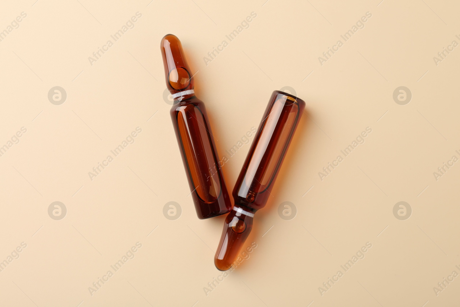 Photo of Glass ampoules with cosmetic product on beige background, flat lay