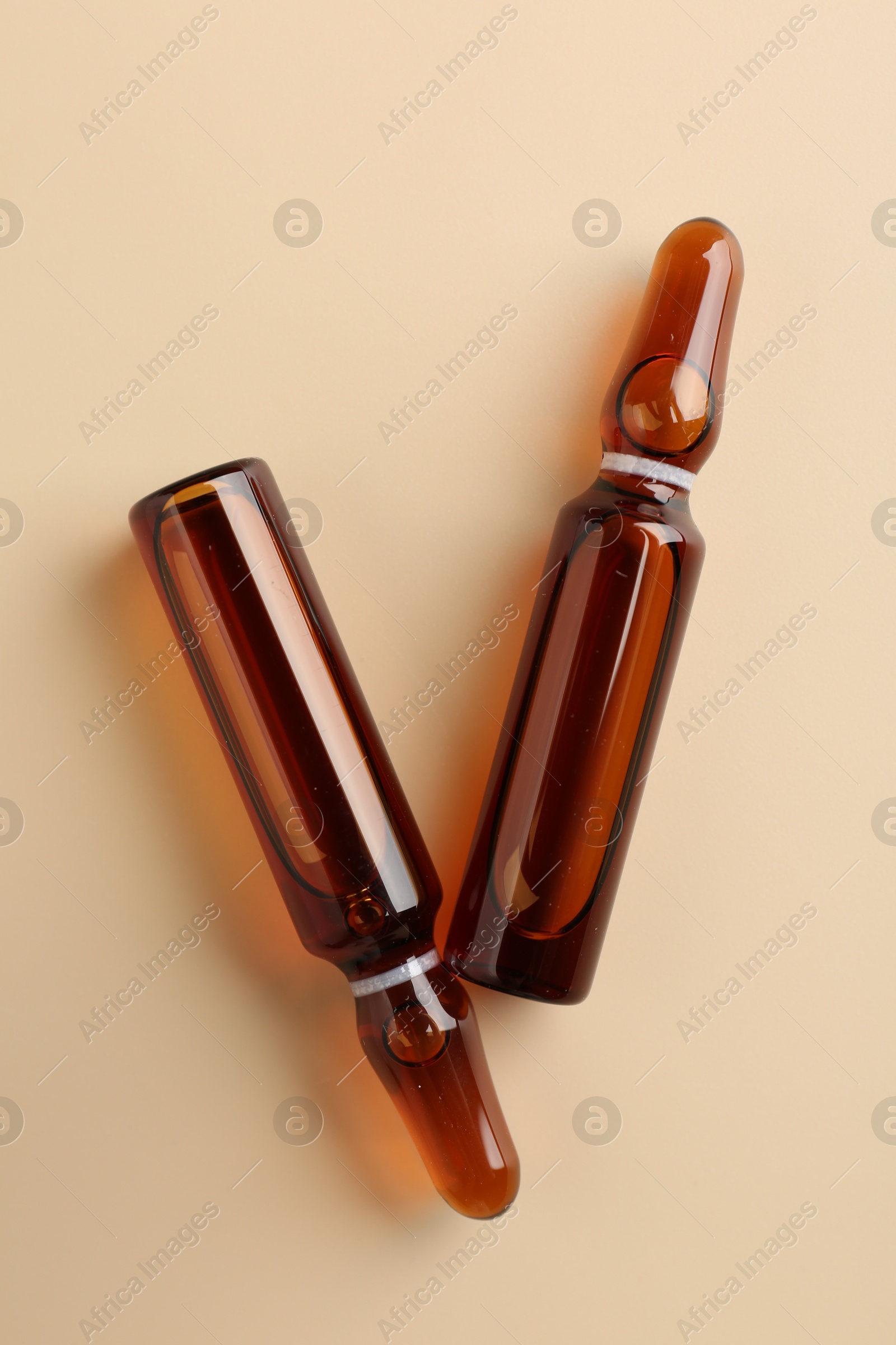 Photo of Glass ampoules with cosmetic product on beige background, flat lay