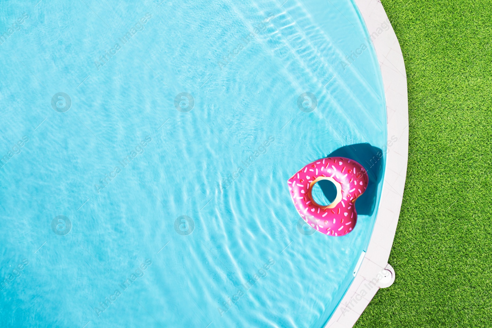 Heart shaped inflatable ring floating in swimming pool surrounded by green grass, top view Image of Heart shaped inflatable ring floating in swimming pool surrounded by green grass, top view