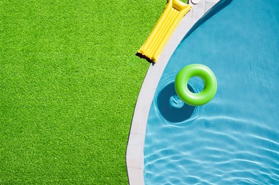 Image of Inflatable ring floating in swimming pool surrounded by green grass, top view