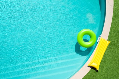 Image of Inflatable ring floating in swimming pool surrounded by green grass, top view