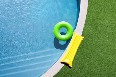 Image of Inflatable ring floating in swimming pool surrounded by green grass, top view