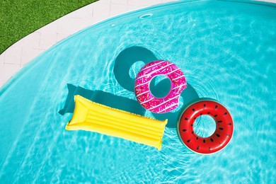 Image of Inflatable rings and mattress floating in swimming pool surrounded, top view