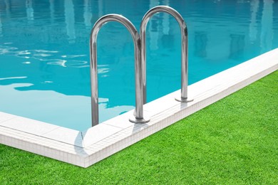 Image of Swimming pool surrounded by green grass outdoors