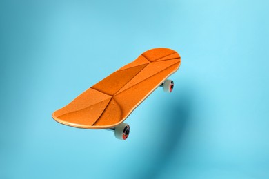 Image of Skateboard with orange pattern in air against light blue background