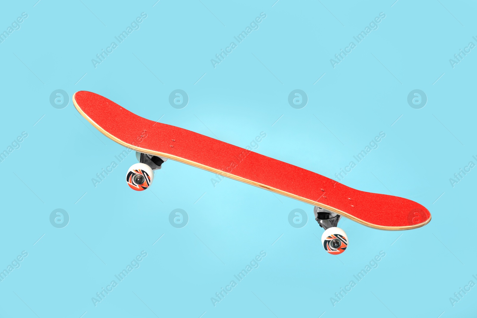 Red skateboard in air against light blue background Image of Red skateboard in air against light blue background