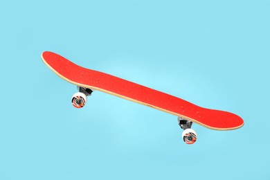 Image of Red skateboard in air against light blue background