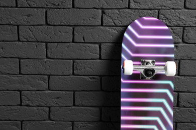 Image of Skateboard with bright pattern near grey brick wall. Space for text