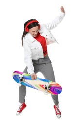 Image of Happy woman jumping with bright skateboard on white background