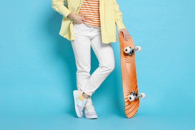 Image of Woman with skateboard on light blue background, closeup