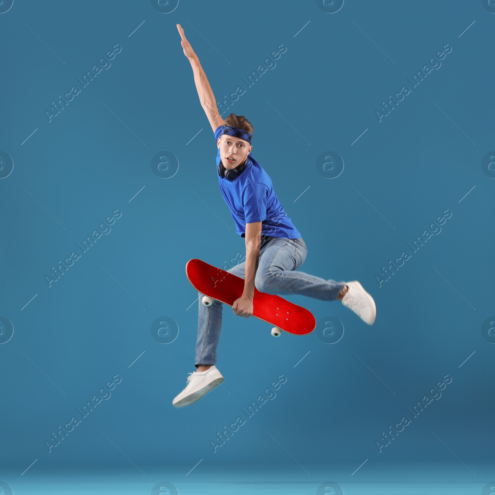 Man jumping with red skateboard on blue background Image of Man jumping with red skateboard on blue background