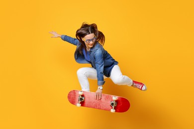 Image of Smiling woman jumping with red skateboard on orange background