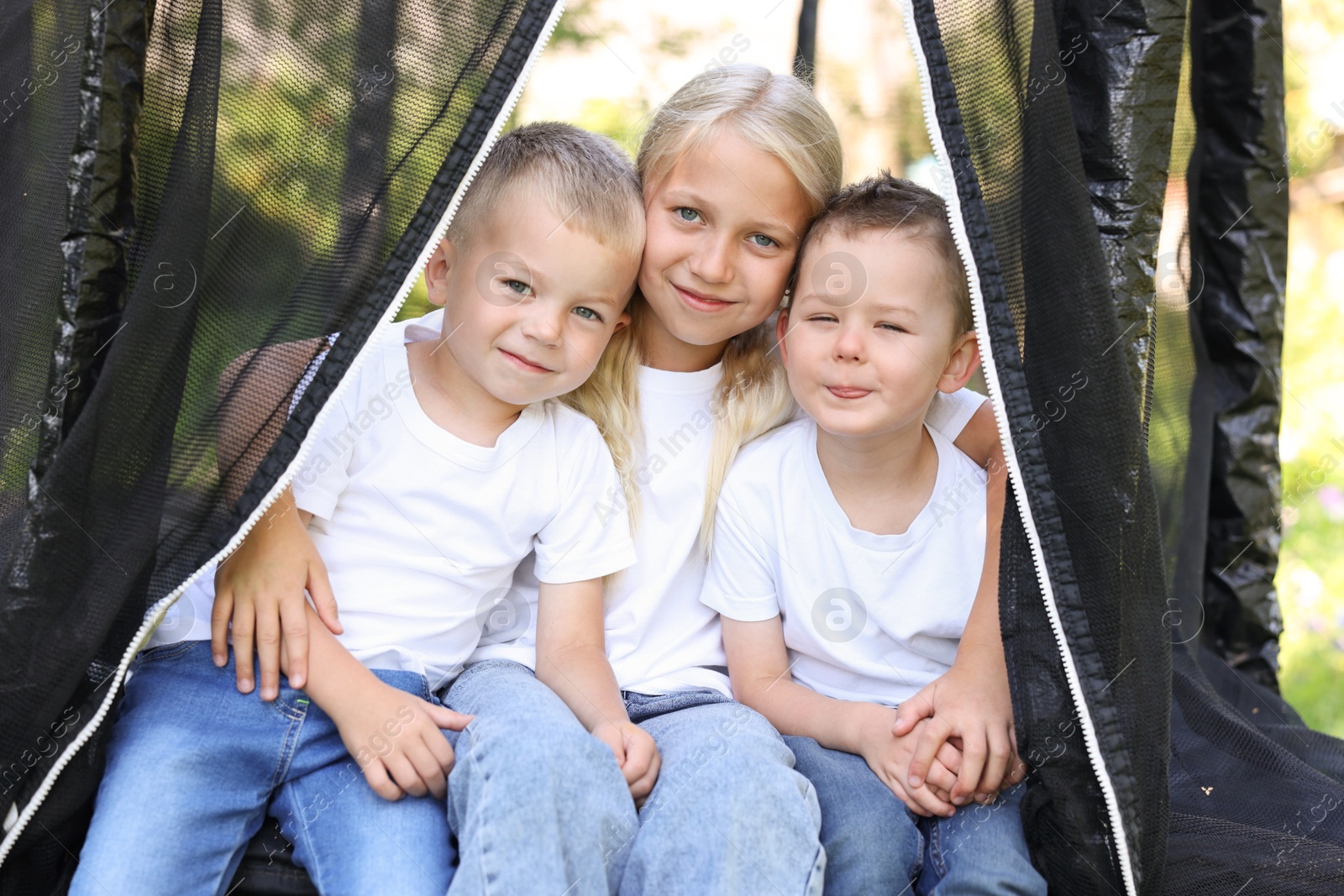 Photo of Happy children posing on black trampoline outdoors