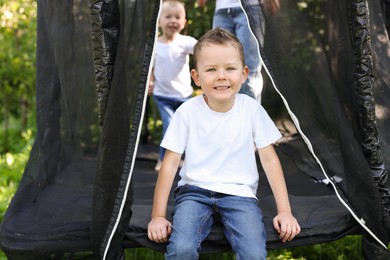 Photo of Happy little boy and his friends on black trampoline outdoors