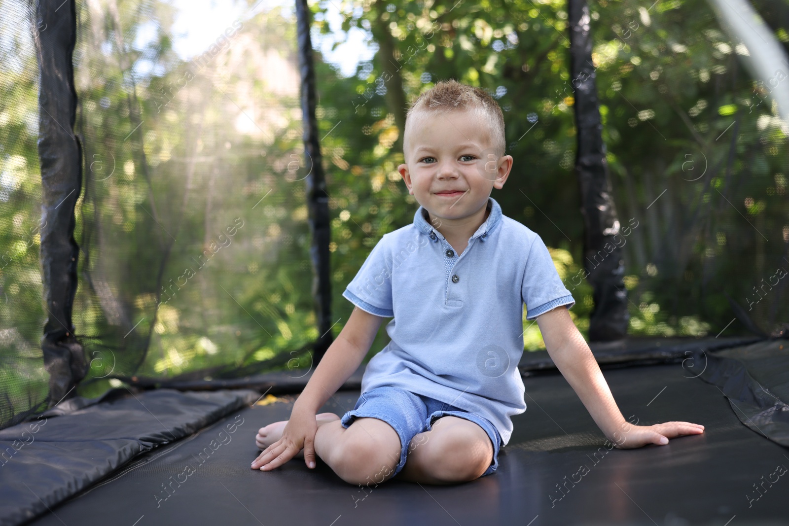 Photo of Cute little boy posing on black trampoline outdoors