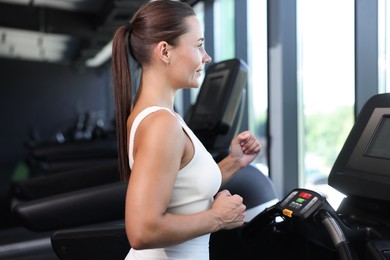 Photo of Athletic woman training on treadmill in gym