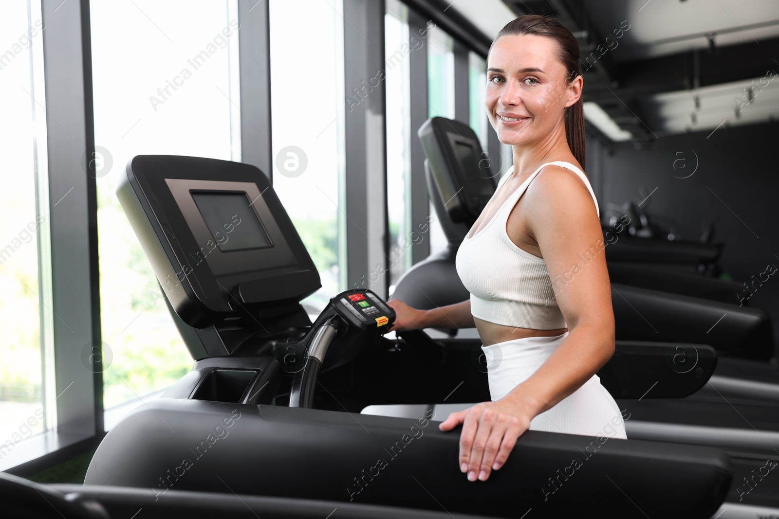 Photo of Smiling woman training on treadmill in gym