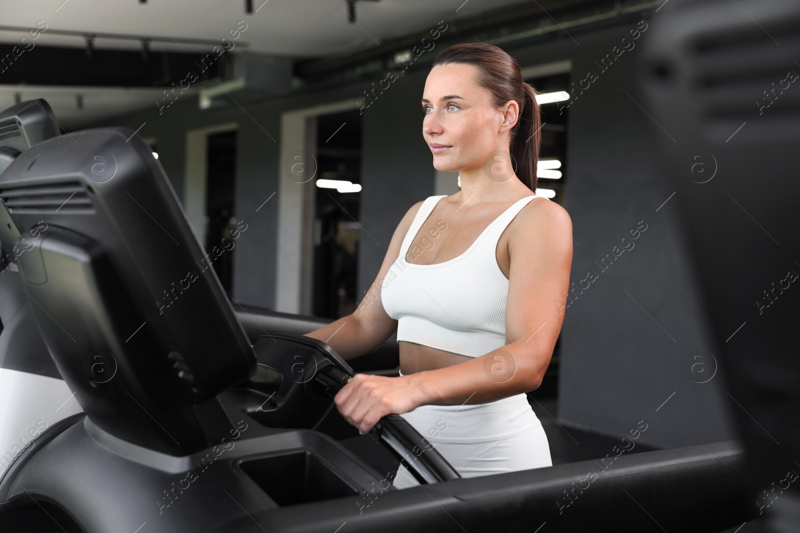 Photo of Athletic woman training on treadmill in gym