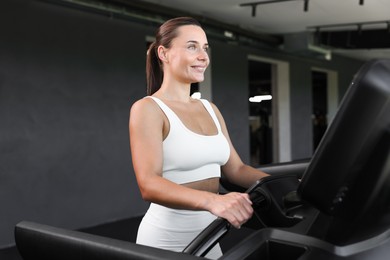 Photo of Smiling woman training on treadmill in gym