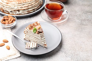 Photo of Piece of tasty crepe cake with cocoa powder, chocolate and nuts served on table