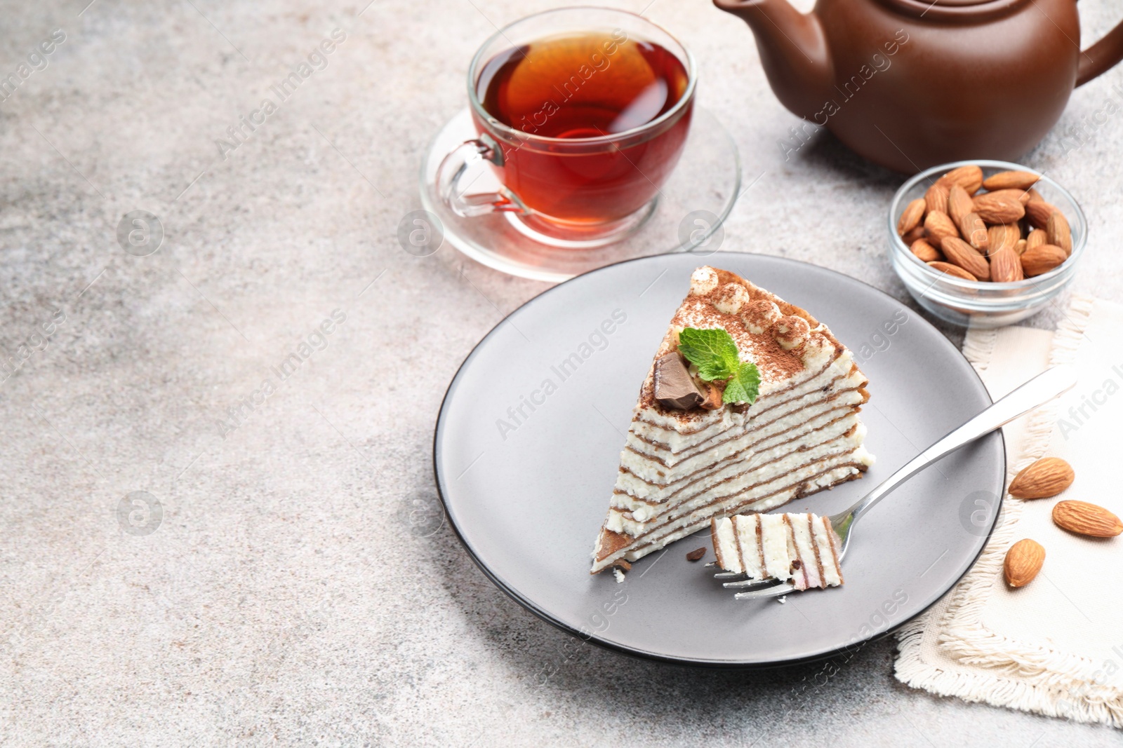 Photo of Piece of tasty crepe cake with cocoa powder, chocolate and nuts served on light table. Space for text