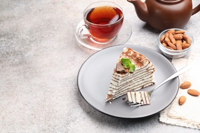 Photo of Piece of tasty crepe cake with cocoa powder, chocolate and nuts served on light table. Space for text
