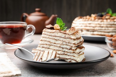 Photo of Piece of tasty crepe cake with cocoa powder, chocolate and nuts served on light table, closeup