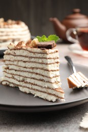 Photo of Piece of tasty crepe cake with cocoa powder, chocolate and nuts served on light table, closeup