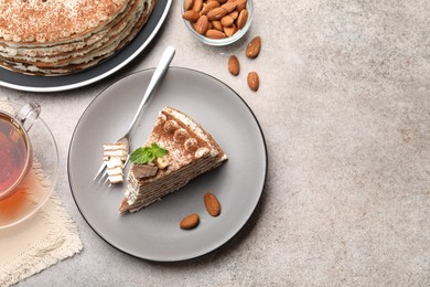 Photo of Piece of tasty crepe cake with cocoa powder, chocolate and nuts served on light table, flat lay. Space for text