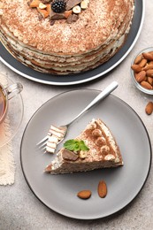 Photo of Piece of tasty crepe cake with cocoa powder, chocolate and nuts served on light table, flat lay