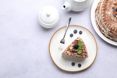 Photo of Piece of tasty crepe cake with cocoa powder, chocolate, nuts and blackberry served on light table, flat lay. Space for text