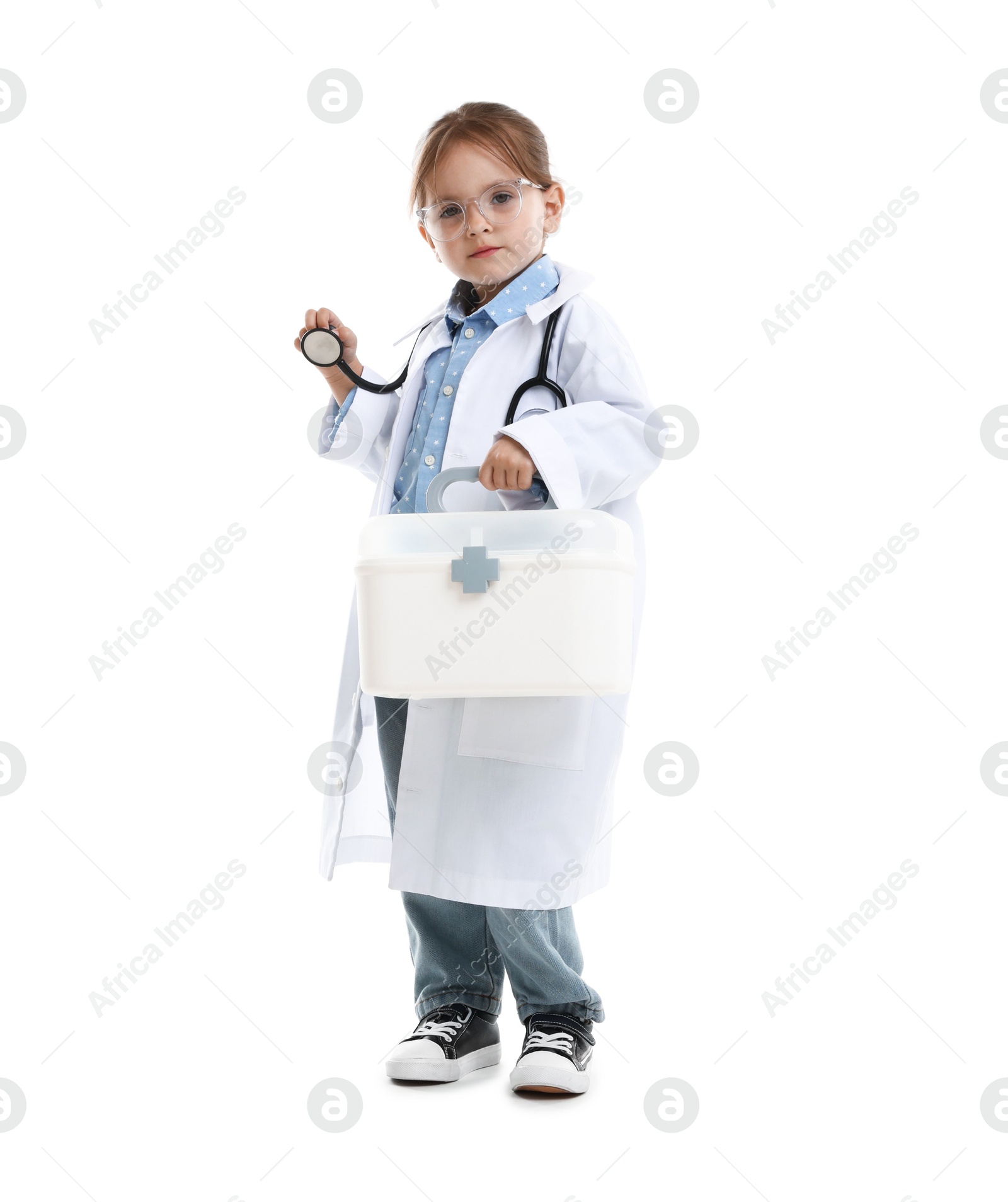 Photo of Choice of profession. Little girl in uniform with stethoscope and case pretending to be doctor on white background