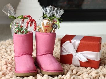 Photo of Saint Nicholas day tradition. Boots with sweets and gift box on floor indoors