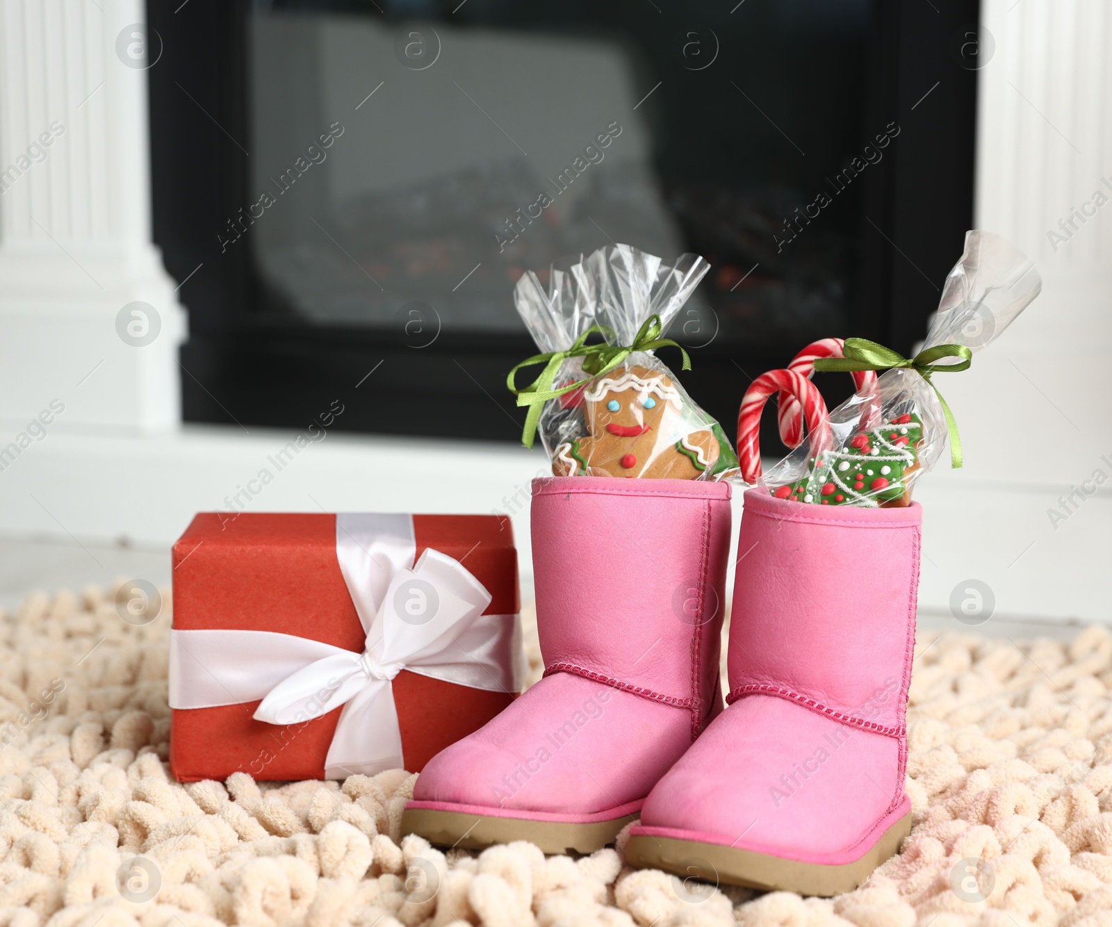Photo of Saint Nicholas day tradition. Boots with sweets and gift box on floor indoors