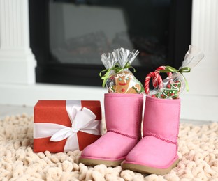 Photo of Saint Nicholas day tradition. Boots with sweets and gift box on floor indoors