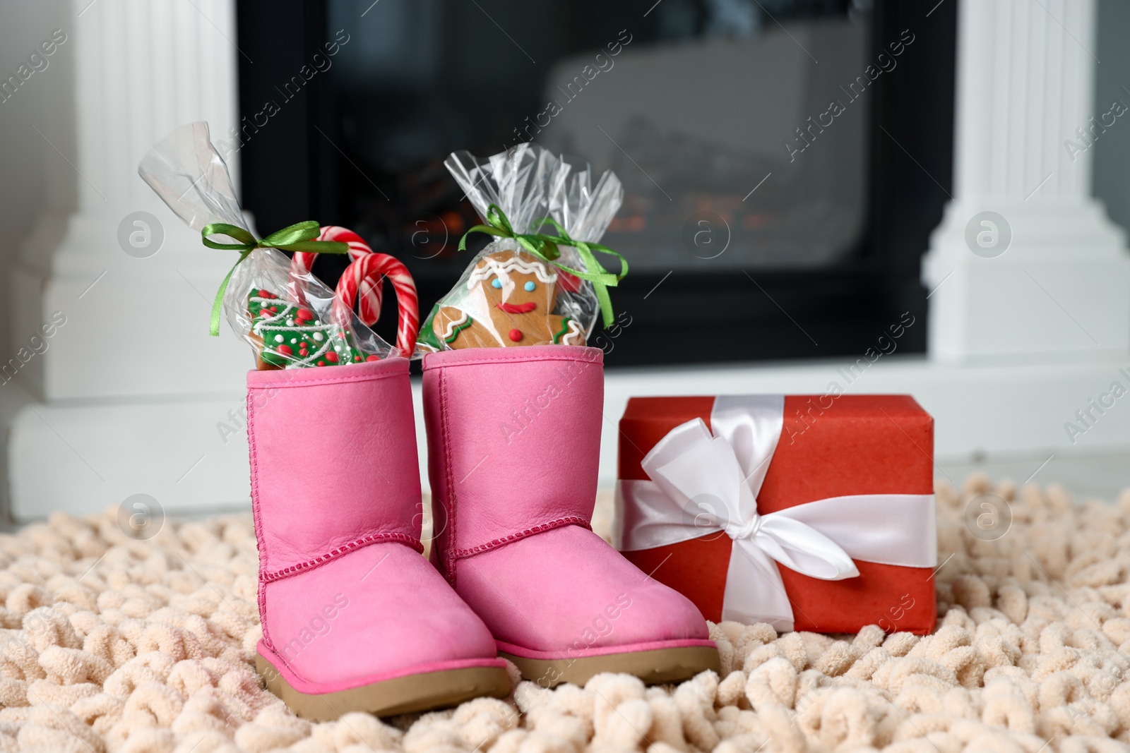 Photo of Saint Nicholas day tradition. Boots with sweets and gift box on floor indoors