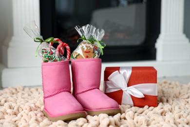 Photo of Saint Nicholas day tradition. Boots with sweets and gift box on floor indoors