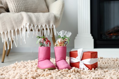 Photo of Saint Nicholas day tradition. Boots with sweets and gift box on floor indoors