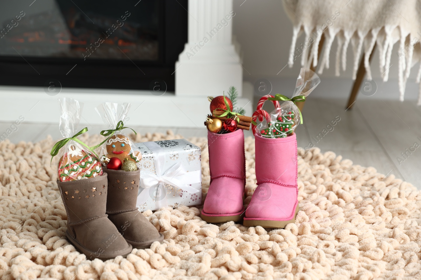 Photo of Saint Nicholas day tradition. Boots with sweets, festive decor and gift box on floor indoors