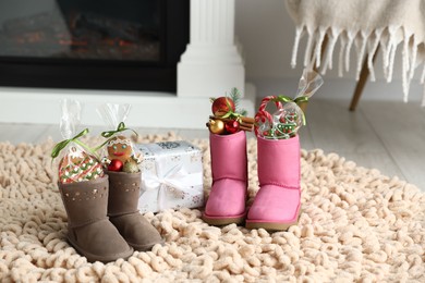 Photo of Saint Nicholas day tradition. Boots with sweets, festive decor and gift box on floor indoors