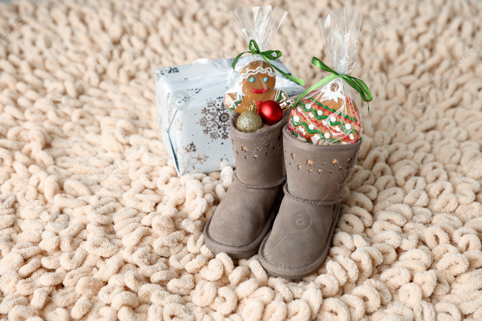Photo of Saint Nicholas day tradition. Boots with sweets, festive decor and gift box on floor indoors