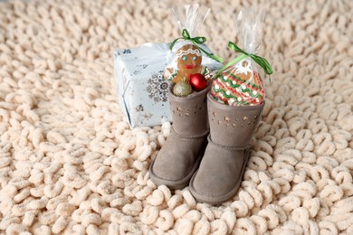 Photo of Saint Nicholas day tradition. Boots with sweets, festive decor and gift box on floor indoors