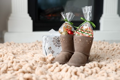 Photo of Saint Nicholas day tradition. Boots with sweets, baubles and gift box on floor indoors, space for text